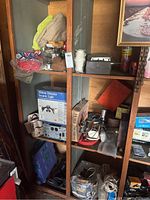 Full view of wooden shelving with various gardening and electrical items, string, and tool bag.
