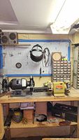 Wide shot of the workbench and pegboard showing the CTT heavy duty grinder, Black & Decker bench grinder, Craftsman toolbox, hardware organizer, and various tools.