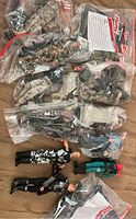 Photo showing multiple GI Joe figures in plastic storage bags on wood floor, some loose figures at front