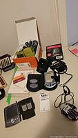 Lot contents including Palm Pilots, vintage cellphone, multi card reader, chargers and accessories on table surface
