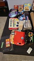 Overhead photo of table with children's games and toys including keyboard, puzzles, books, and story reader