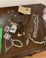 Assorted jewelry on wooden surface including necklaces, earrings, rings and bracelets shown full lot