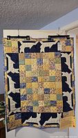 Full view of the handmade patchwork lap quilt titled "My Quiet Garden," showing the central floral square pattern and dog silhouette border.