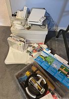 Nintendo Wii console system, controllers, Sports Kit Pro kit, games and Wii Fit balance board arranged on a chair and boxes for overview of all items in lot
