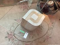 Overview of the coffee table with glass top and stone base showing overall shape and size on a floral carpet