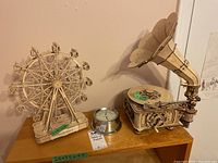 Ferris wheel and gramophone models on wooden table with Airguide wall thermometer and barometer beside them
