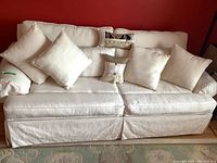 Full front view of white upholstered sofa with seven matching cushions arranged on backrest.