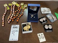 Photo showing the full lot with necklaces, earrings sets in boxes, and loose earrings displayed on table.