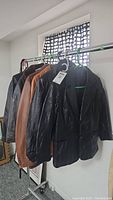 Five leather coats hanging on rack, showing colors and styles