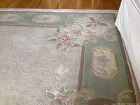 Close-up of floral patterned border of wool rug showing color, pile texture and design detail.