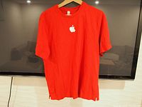Front view of red Apple t-shirt with large white embroidered Apple logo centered on chest.
