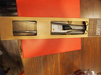 Boxed packaging of Grillight stainless steel LED lighted tongs showing product through window with text information on front of box.