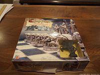 The closed original box with Harry Potter branding and chess pieces pictured on the box front, with a clear window showing one black horse chess piece inside.