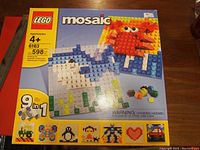 Photo of the LEGO Mosaic 6163 box showing the assembled mosaic crab and shark designs, 9 possible mosaic images, recommended age 4+, and piece count of 598.