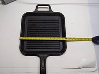 Top view of the square cast iron grilling pan with measuring tape showing about 12 inches width.