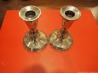 Pair of polished sterling silver candlestick holders viewed from the top showing flared candle cups and wide bases.