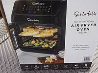 Box of Sur La Table Multifunctional Air Fryer Oven showing cooking capabilities and brand.