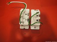 Rear view of two white TP-Link Kasa Smart Wi-Fi dimmer switches with wiring visible on red background.