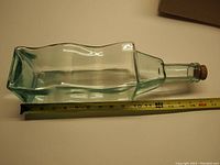 Photo showing the bottle lying horizontally next to a measuring tape indicating a length of about 13 inches.