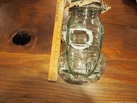 Vintage Italian glass VW Beetle shaped cookie jar with ruler for size reference, hinged clasp lid is slightly open, clear heavy glass shows detailed car contours.