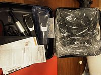 Complete haircutting and trimming tools arranged in carrying case with manuals visible