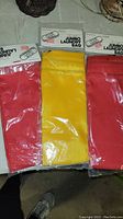 Photo showing three jumbo laundry bags sealed in packaging; two red and one yellow.