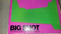 Close-up photo of top of box showing bright pink and green colors with 'BIG SHOT POLAROID PORTRAIT LAND CAMERA' lettering.