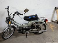 Full left side view of moped showing frame, saddle, engine, exhaust