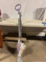 Side and front view of the purple and gray Shark steam mop with two white mop pads attached to the mop head.