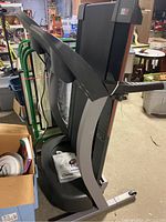 Side view of treadmill unfolded in a storage or garage area with user manual placed on base.