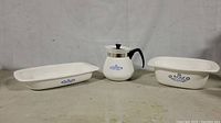 Three vintage Corning Ware items: two rectangular dishes and one coffee pot with blue cornflower pattern.
