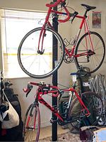 Two red road bikes mounted vertically on the bike rack to show usage and how the rack holds bikes.