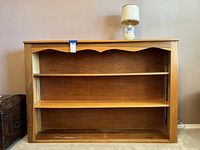 Wood bookshelf with scalloped edge and two adjustable shelves, medium brown finish.