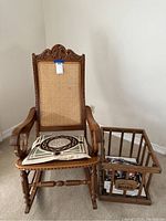 Full view of custom wooden rocking chair with woven cane back and seat, featuring a cushion, next to wooden crate rack.