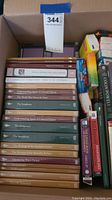 Top-down photo of box containing DVD cases stacked vertically showing mostly spine labels of The American Civil War, The Symphony, The Old and New Testaments, and other educational titles.