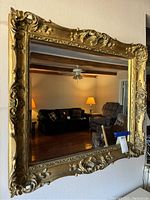 Front view of large rectangular gold trim mirror showing ornate carved frame and clear reflective glass.