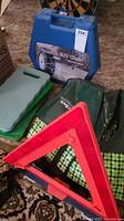 Overall lot showing blue case with truck & SUV chain label, red emergency triangle, and kneeling pads on patterned carpet.