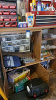 Full view of wooden storage cabinet with shelving holding various tools and hardware, Craftsman toolbox on top, and associated items on bottom shelves.