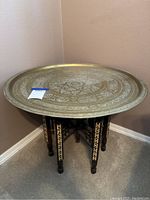Brass tray seated on wooden stand, full view of lot