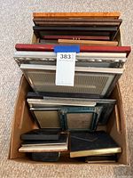 Top-down view of one box containing a variety of picture frames with assorted colors and sizes.