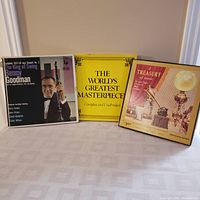 Photo showing three classical and swing music LP album sets: 'The King of Swing' by Benny Goodman, 'The World's Greatest Masterpiece', and 'A Treasury of Music'. Albums are displayed upright on a table with their front covers visible.