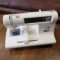 Front view of white Brother sewing/embroidery machine with removable extension table and LCD control panel
