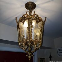Ceiling fixture lit showing detailed etched glass and brass design