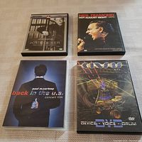 Four concert music DVDs arranged in a square showing Joe Cocker, Neil Diamond, Paul McCartney, and Kansas concert films