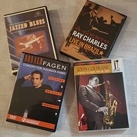Four DVD cases showing covers featuring Ray Charles, John Coltrane, Donald Fagen, and Jazzed Blues instructional guitar DVD.