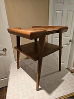 Full view of solid oak side table with tapered legs and lower shelf, showing shape and structure.