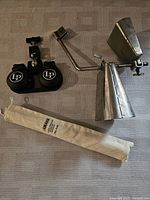 Two black drum-mounted castanets with LP logo, vintage silver metal cowbell on mounting arm, and beige Yamaha cloth bag for recorder.