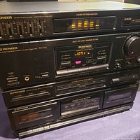 Close-up photo of the Pioneer RX-750 receiver showing display and controls, cassette deck below, and spectrum analyzer on top