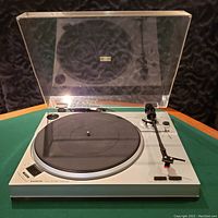 Front angled view of Sanyo turntable with dust cover open, showing control buttons, tonearm, platter with rubber mat