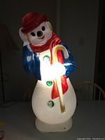 Snowman holiday blow mold lit up, showing interior light and candy cane detail